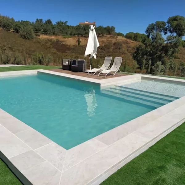 Piscina con borde de pastelones de gran formato integrado al pasto