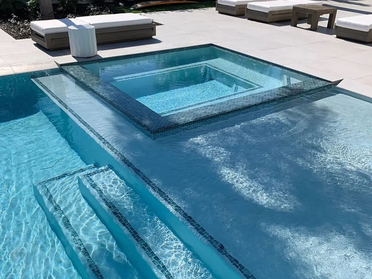 Piscina revestida en Diamond Brite color Blue Quartz, con spa integrado y peldaños sumergidos