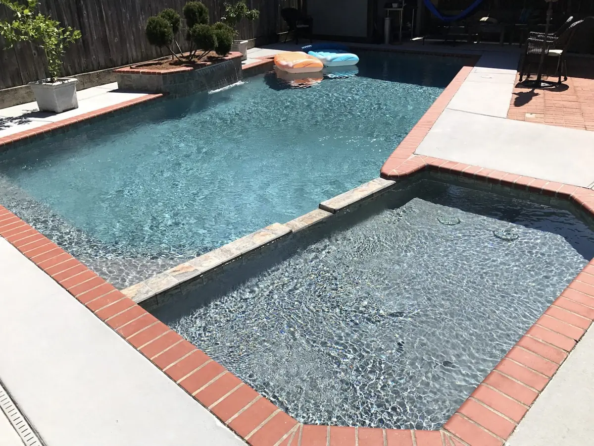 Piscina revestida en Diamond Brite color French Gray, con borde de ladrillo