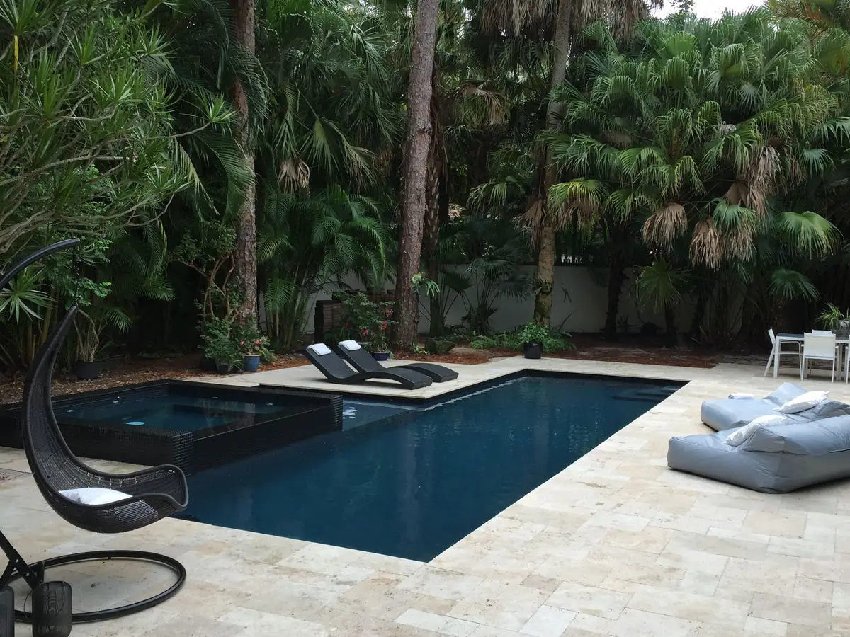 Piscina revestida en Diamond Brite color Onyx, de agua oscura, rodeada de palmeras