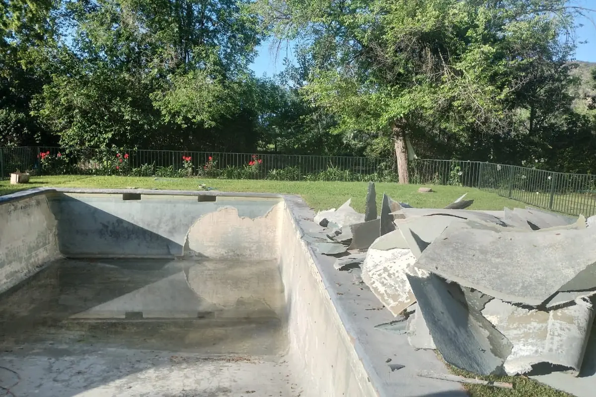 Piscina vaciada con los trozos del revestimiento antiguo retirados y apilados en el borde