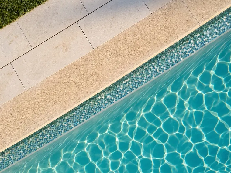 Borde de piscina en diagonal, con la franja de mosaico bajo la línea de agua