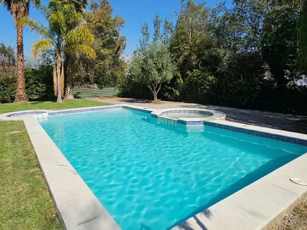 Piscina rectangular revestida en Marble Dust, con spa integrado y borde de pastelones
